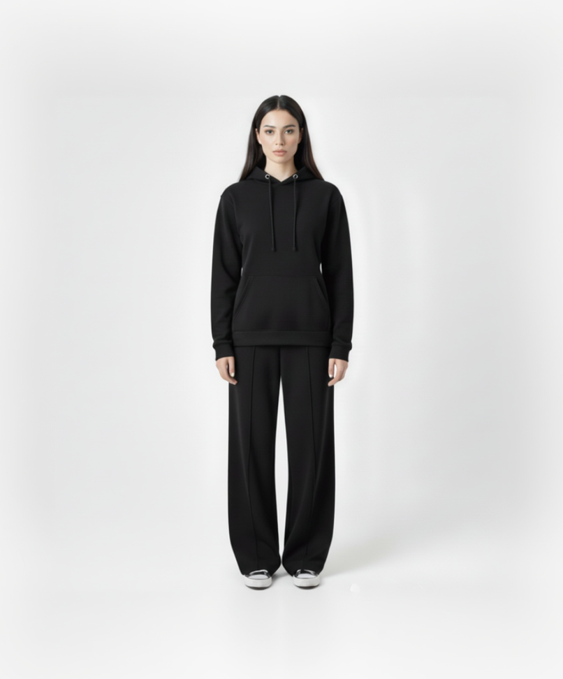 Person wearing a black hoodie and black pants on a white background