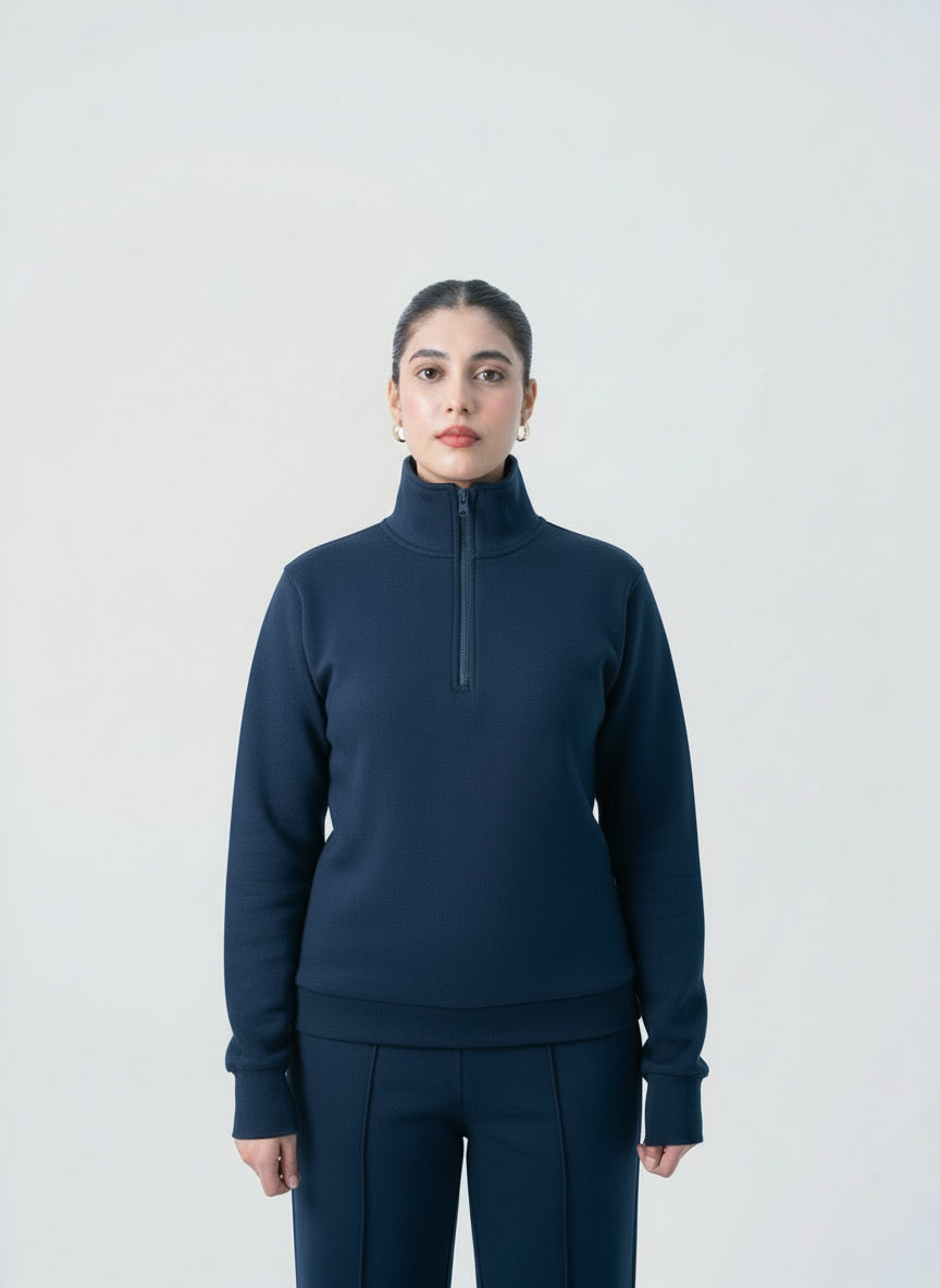 Person wearing a navy blue pullover with a quarter zip on a light gray background