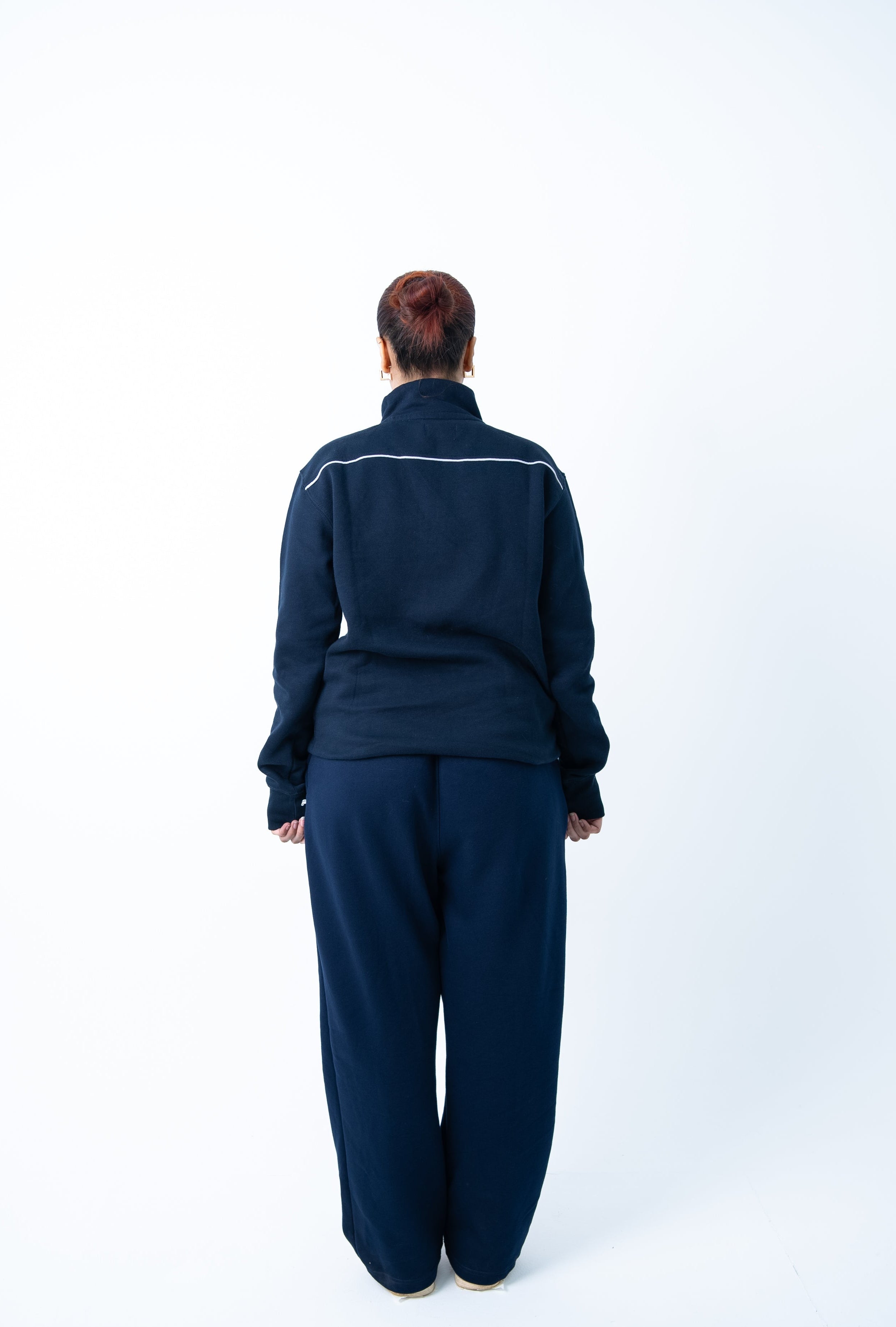 Person wearing a navy tracksuit on a white background