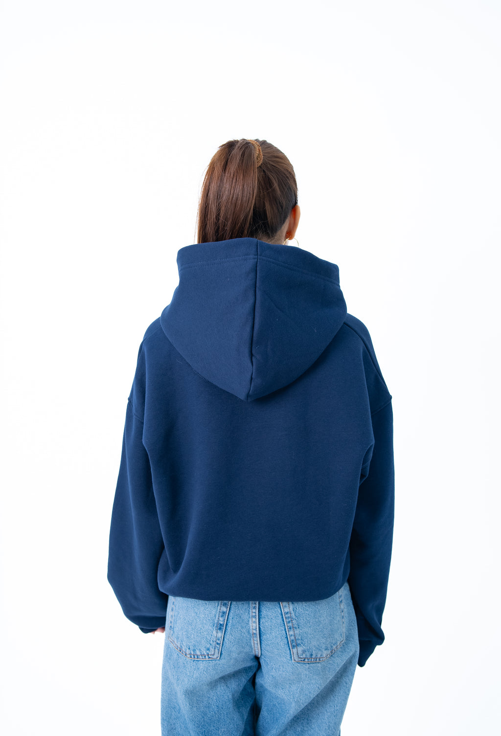 Person wearing a blue hoodie and light blue jeans on a white background