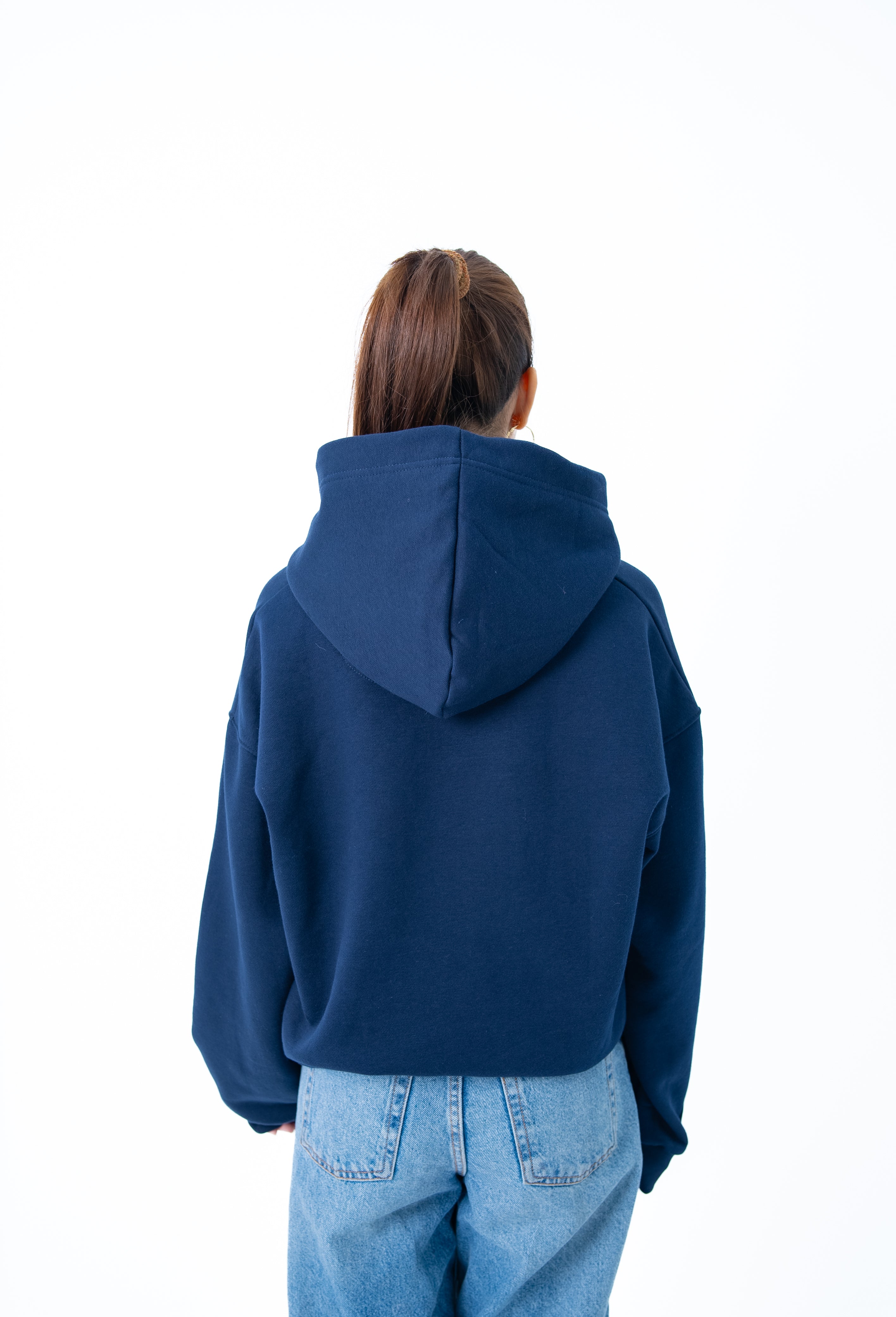 Person wearing a blue hoodie and light blue jeans on a white background