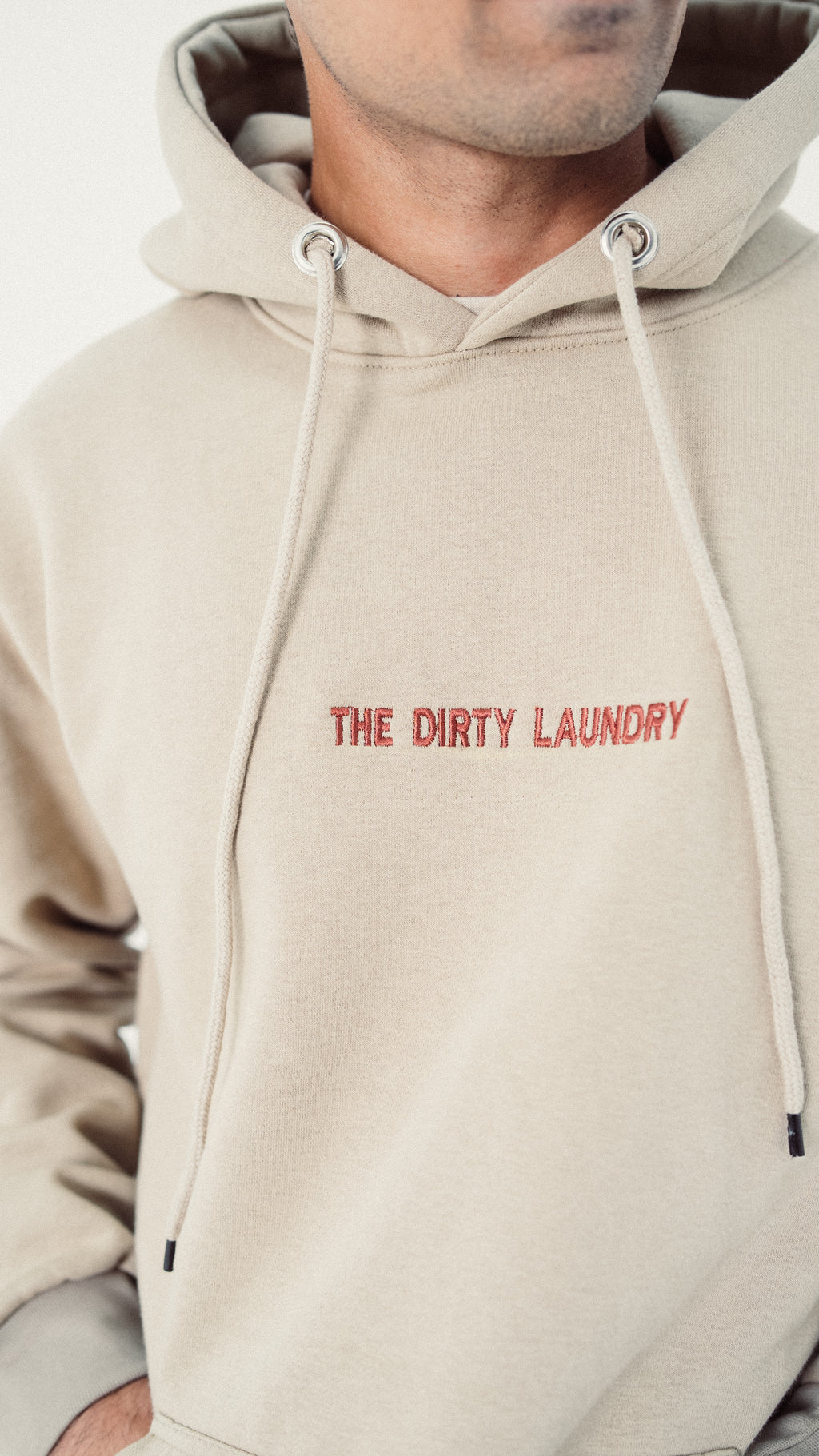 Beige hoodie with 'The Dirty Laundry' text on a plain background
