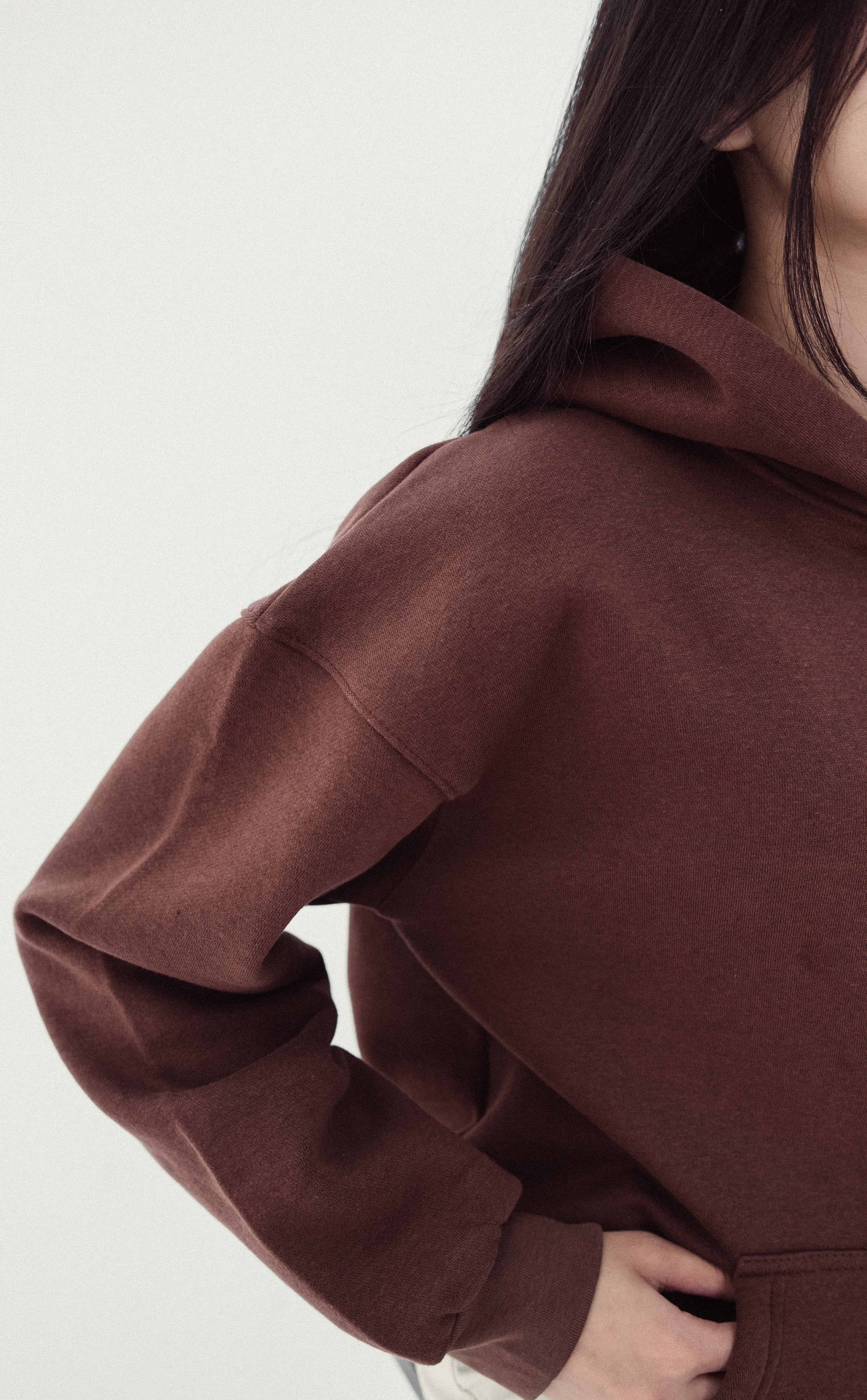 Brown hoodie worn by a person on a light gray background
